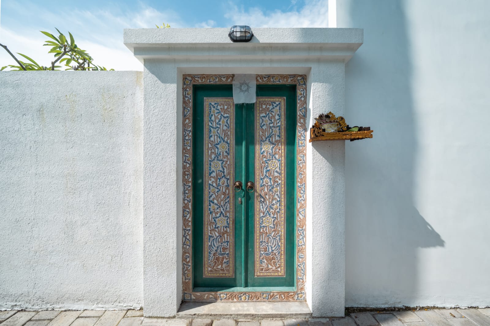 Carved teal entrance doors in a white wall